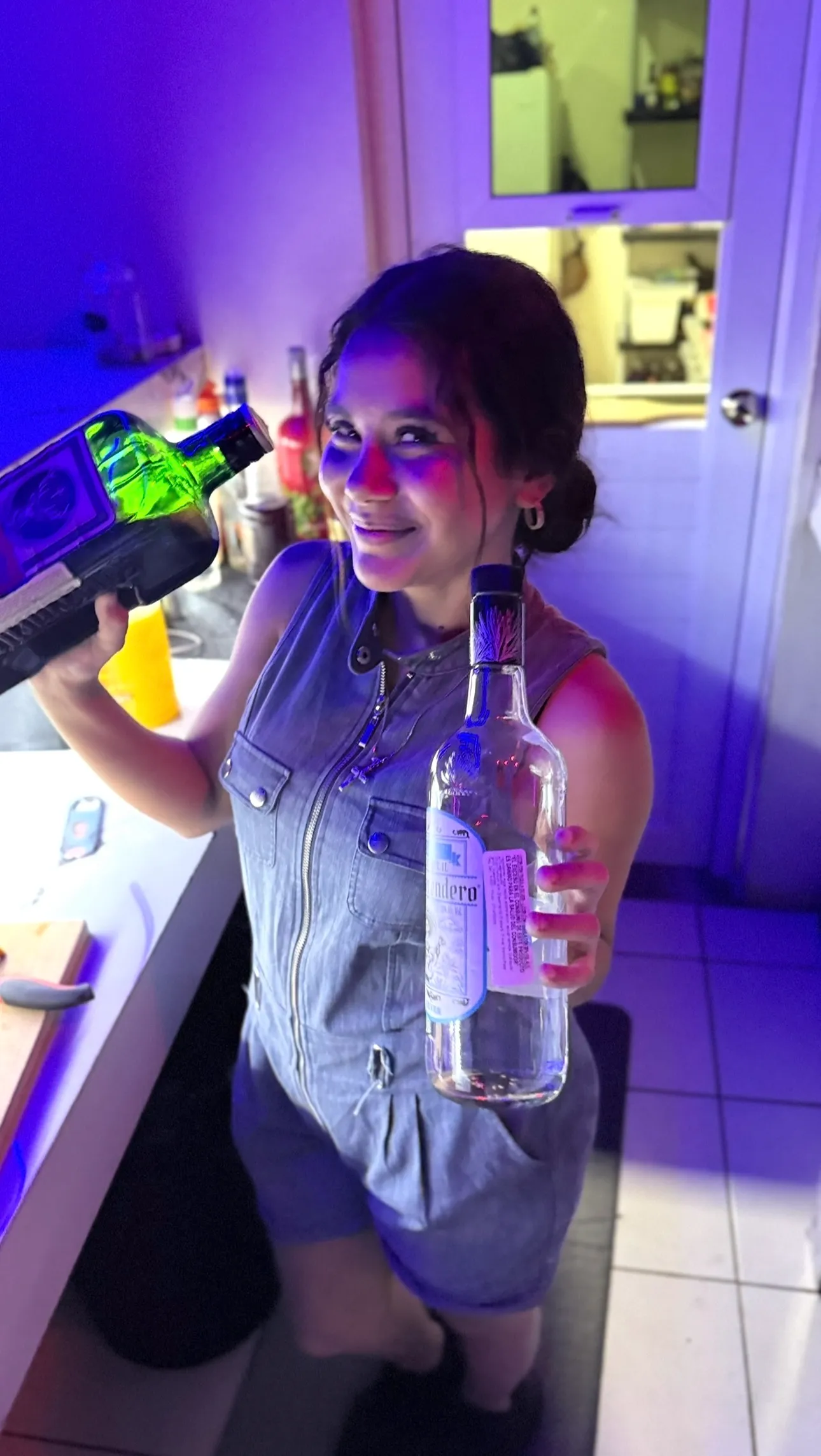 Bartender sosteniendo botellas con luces neon azules