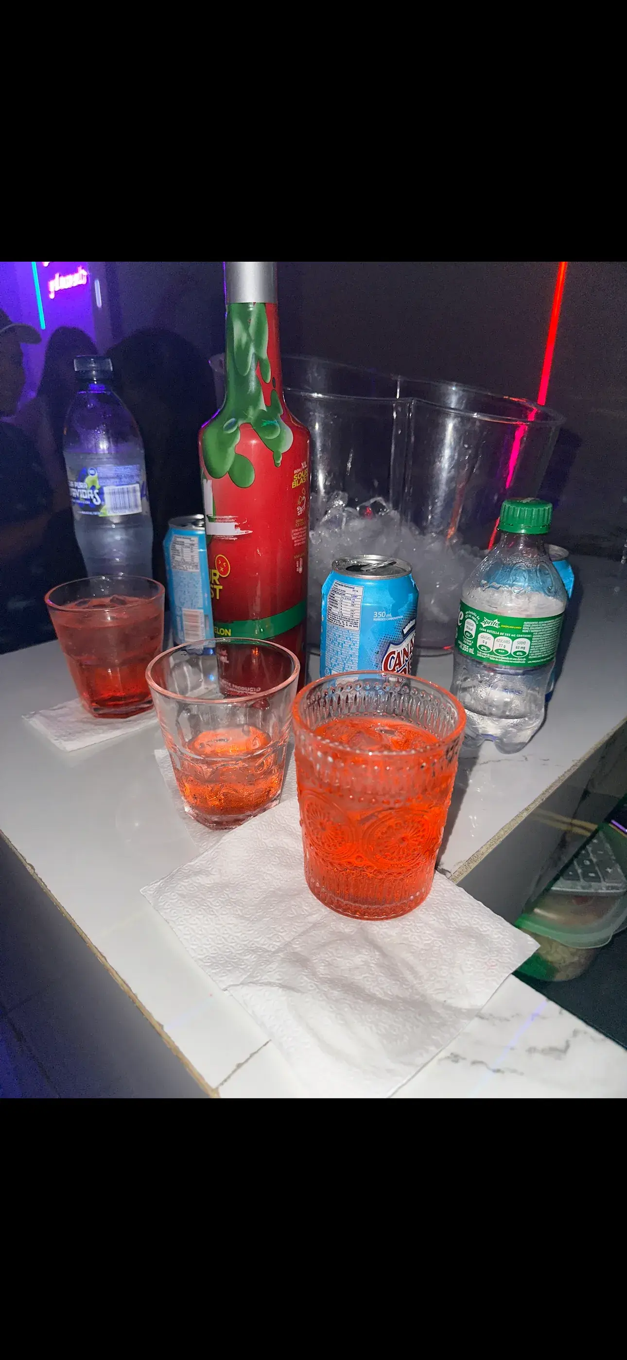 Bebidas y botellas en mesa con luces neon