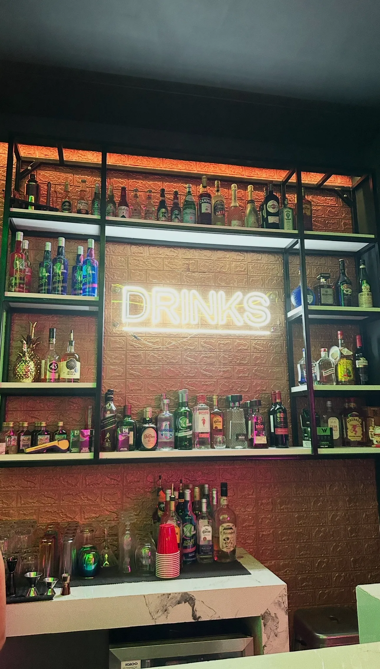 Estante de licores premium con letrero neon DRINKS