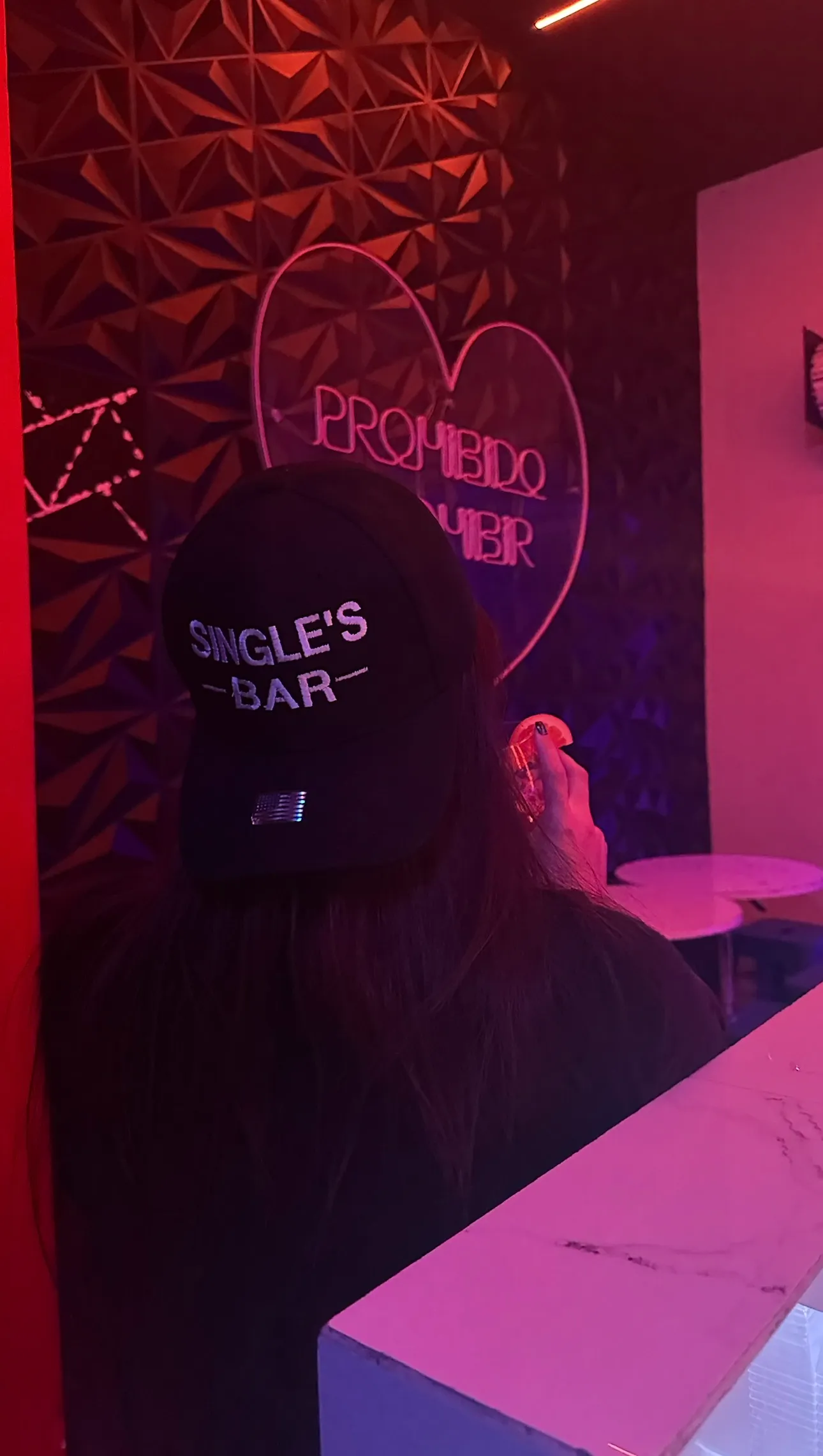 Persona con gorra Single's Bar frente a neon