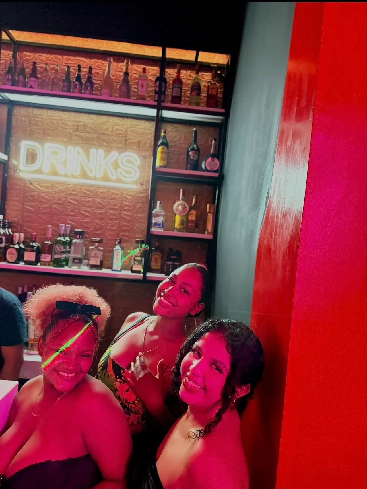 Grupo de amigas en la barra con letrero DRINKS