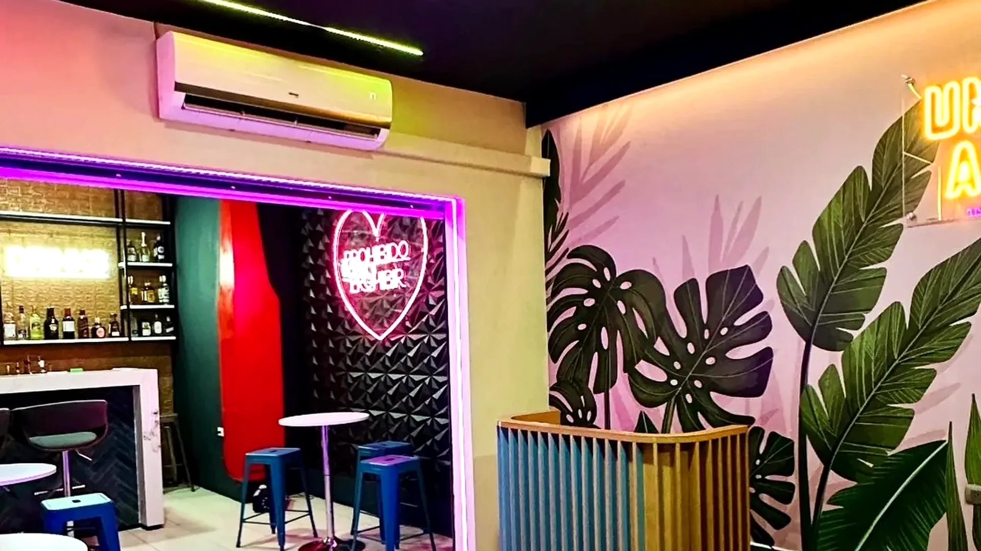 Interior real de Single's Bar con mesas y mural tropical