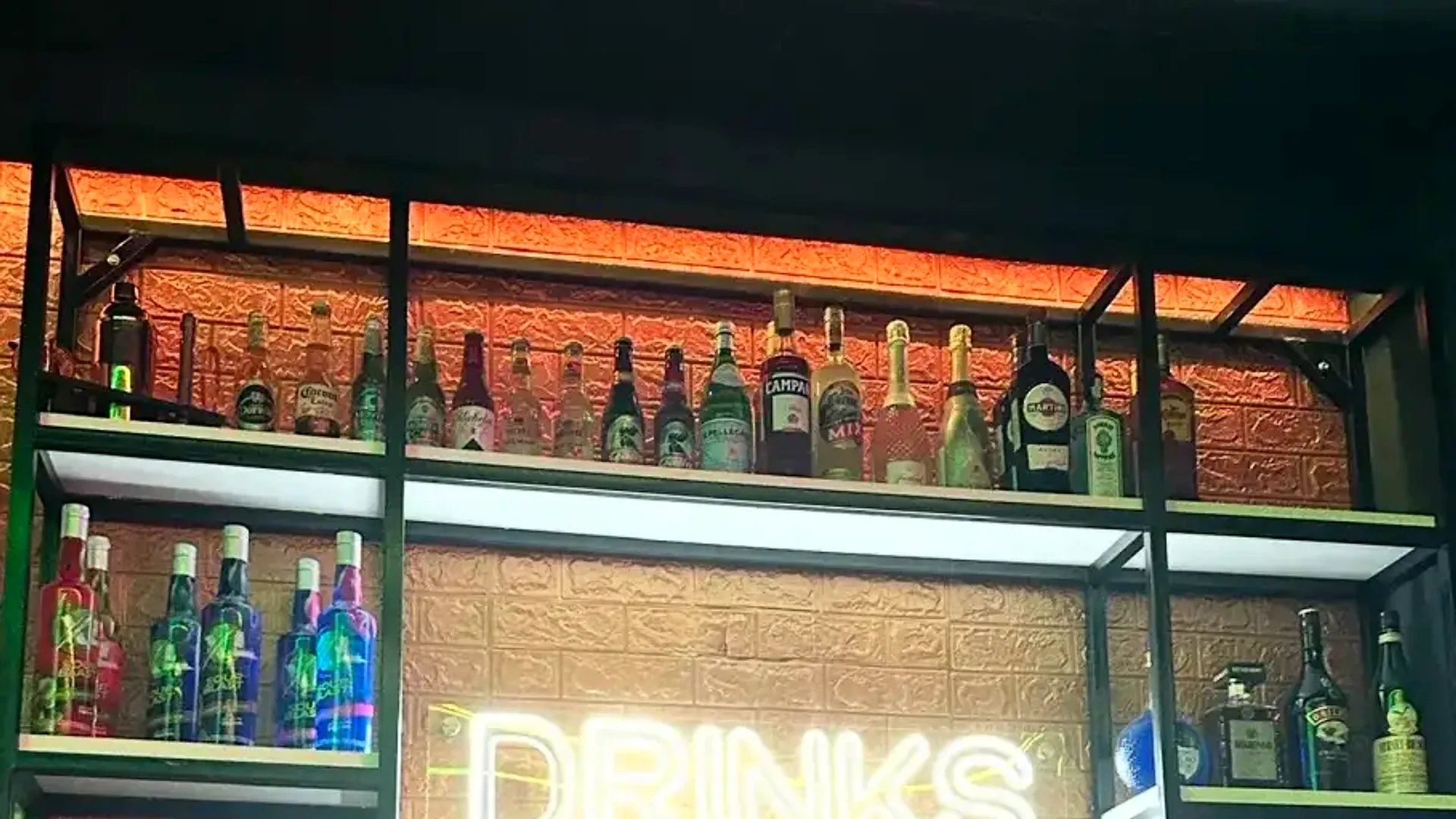 Estante de licores premium con neón DRINKS en Single's Bar